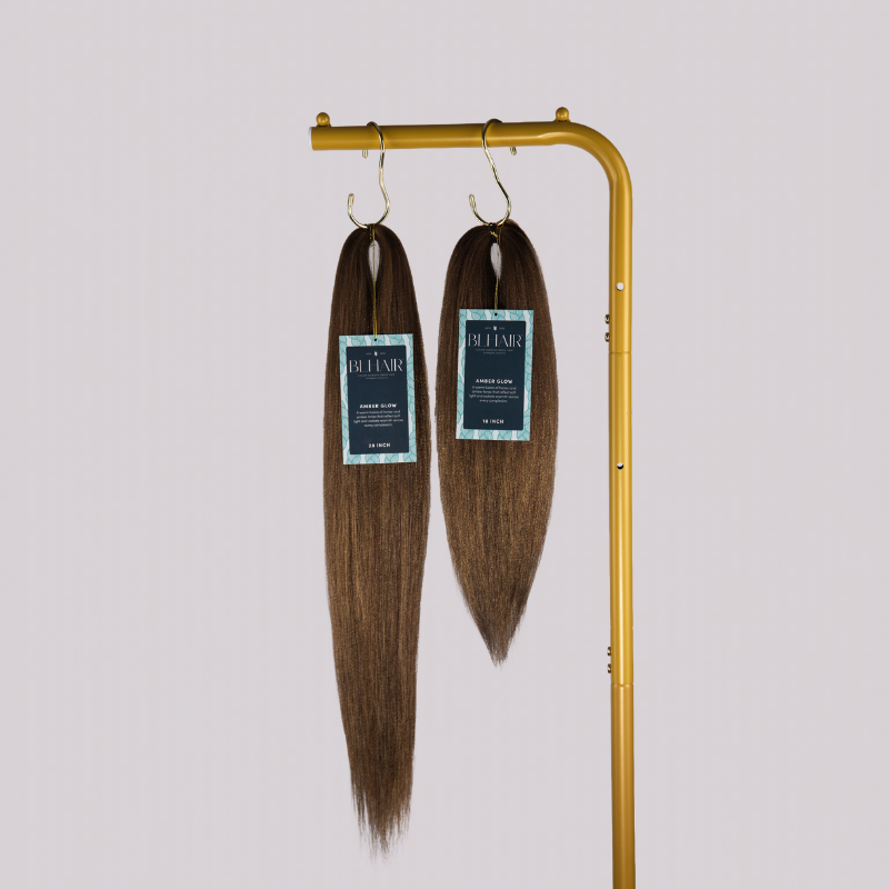Two Blhair™ Amber Glow braid hair bundles displayed on gold stand against neutral background.