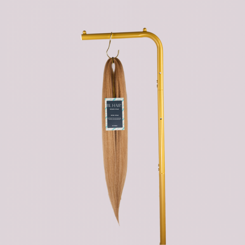 Blhair™ Rose Gold braid hair bundle hanging on gold stand against neutral background.